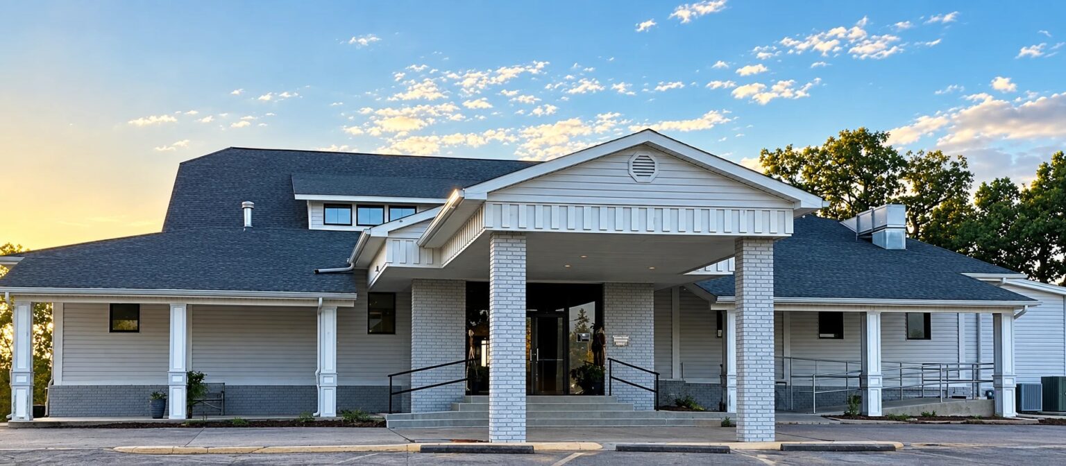 The McAlester Country Club clubhouse, a white building with columns, seen from the lawn